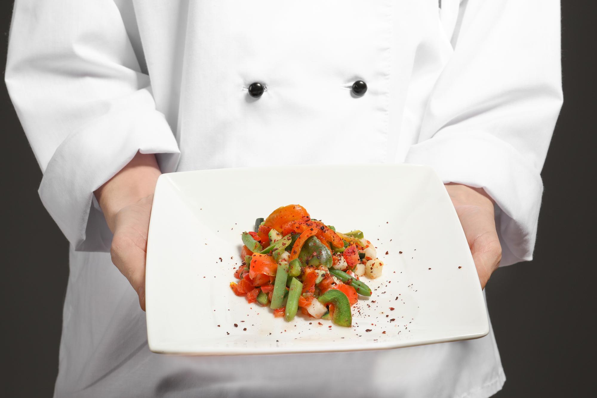 Instructor plating a composed dish in studio kitchen